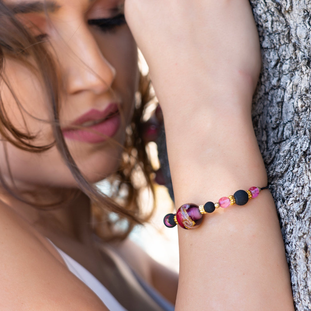 Modella indossa bracciale di ungioielloperte.com con perla centrale in vetro di Murano rosa e dettagli in metallo dorato