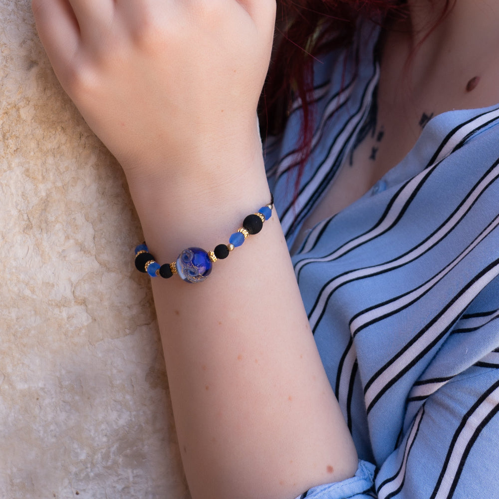 Modella indossa bracciale di ungioielloperte.com con perla centrale in vetro di Murano blu e dettagli in metallo dorato